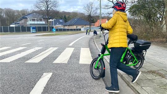 Ein Radfahrer schiebt sein Fahrrad über einen Zebrastreifen.