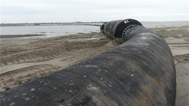 Wie eine dicke Schlange liegt die Leitung, durch die das Wasser-Sand-Gemisch schießt, auf dem Krautsander Hundestrand und führt schließlich als 870 Meter lange Schwimmleitung zur Vox Ariane.