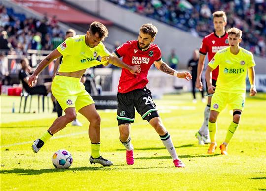 Wiesbadens Thijmen Goppel (l) und Hannovers Kolja Nuno Oudenne (M) kämpfen um den Ball.