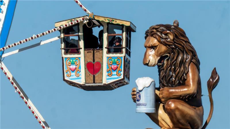 Bilder des Tages Wiesn-Besucher fahren in einem Riesenrad auf dem 190. Münchner Oktoberfest an der Kulisse einen überdimensionalen Löwen mit Bierkrugs vorbei.