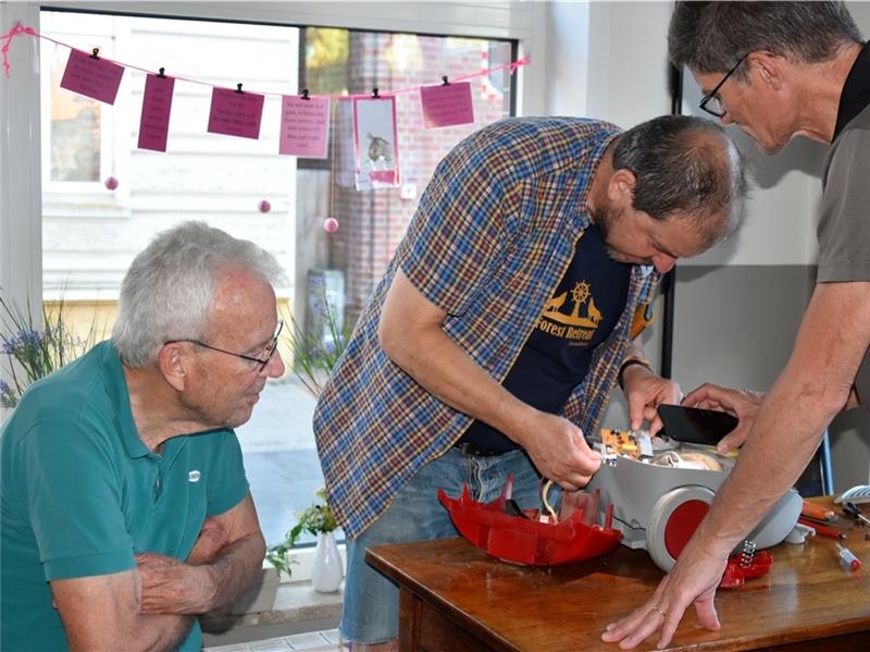 Repair-Café in Estebrügge: Fachsimpeln über altes Gerät und neue Kontakte Wilfrid Schweiger-Lemgo (links) und Lutz Wörner (rechts) schauen Steffen Gill zu, wie er den Staubsauger repariert. Fotos: Felsch
