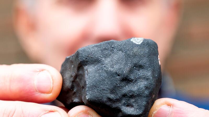 Wilfried Labusch aus Elmshorn hält vor seinem Haus einen kleinen Meteoriten, der niedergegangen ist.