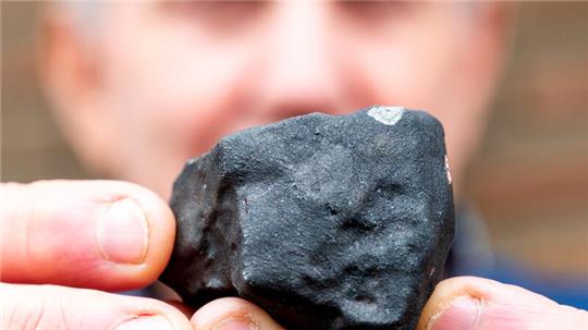 Wilfried Labusch aus Elmshorn hält vor seinem Haus einen kleinen Meteoriten, der niedergegangen ist.