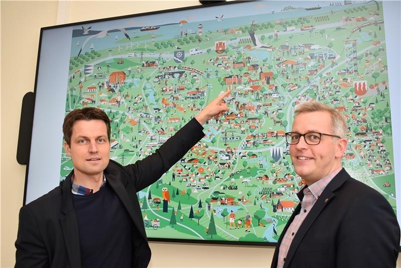 Wimmelwerk-Geschäftsführer Mark Schober aus Nottensdorf und Bürgermeister Knut Willenbockel stellen das Wimmelbild für die Samtgemeinde Horneburg vor (von links), in der Mitte ist das Rathaus zu sehen. Alle fünf Mitgliedsgemeinden sind abge