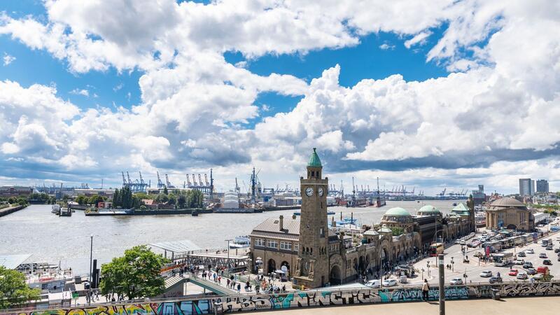 Wind treibt Regenwolken über den Hafen Hamburgs und die Landungsbrücken.