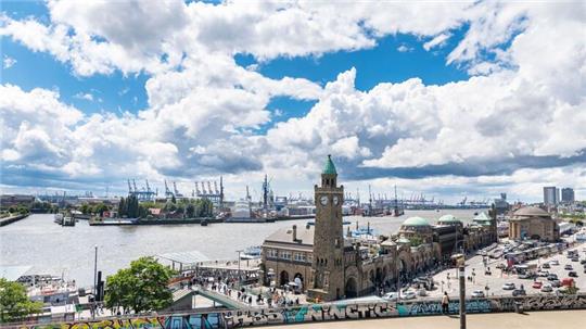 Wind treibt Regenwolken über den Hafen Hamburgs und die Landungsbrücken.