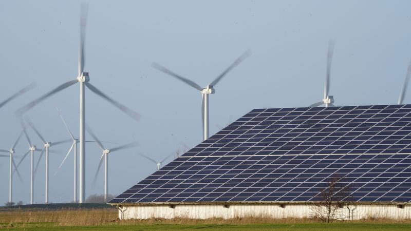 Gleichstromleitung von Heide nach Schwerin Windenergieanlagen stehen neben einer Halle mit Photovoltaik-Anlagen auf dem Dach.