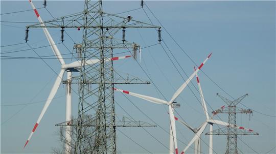 Windkraftanlagen und Strommasten - beides steht für den Ausbau erneuerbare Energie. (Symbolbild)