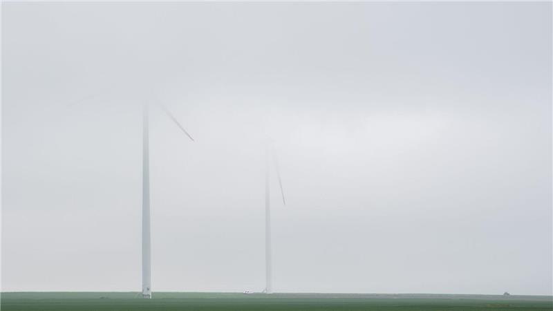 Windräder verblassen bei Regen in tief hängenden Nebelschwaden in der Region Hannover.