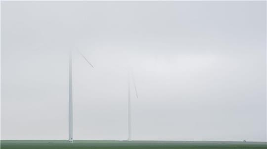 Windräder verblassen bei Regen in tief hängenden Nebelschwaden in der Region Hannover.
