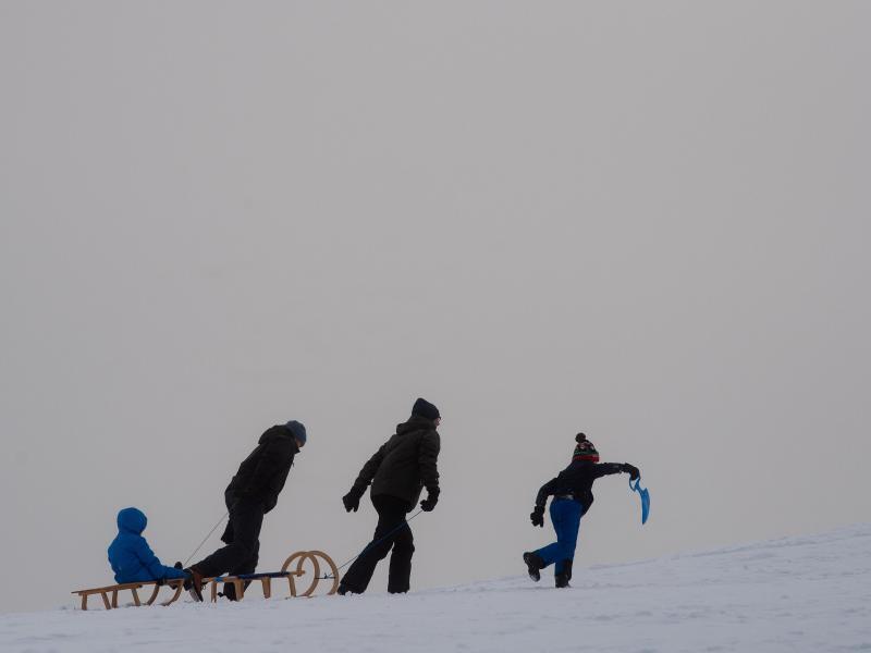 Wintersportler gehen einen Rodelhang am Sonnenberg hinauf. Foto: Swen Pförtner/dpa