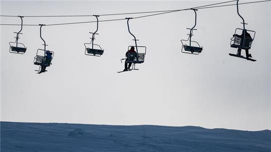 Wintersportler sitzen am Matthias-Schmidt-Berg im Harz in der Seilbahn.