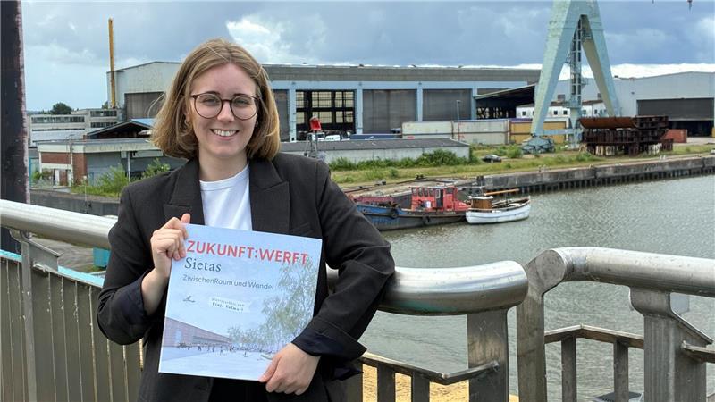 Wohnen und Gewerbe: Finja Volmari zeigt ihre Masterarbeit „Zukunft Werft“, im Hintergrund ist das 14,7 Hektar große Sietas-Gelände mit dem Jucho-Portalkran in Neuenfelde zu sehen.