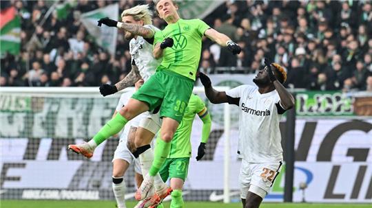 Wolfsburgs Patrick Wimmer (M) und Leverkusens Robert Andrich (l) im Kopfballduell. 