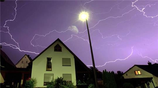 Zahlreiche Blitze sind über einem Wohnhaus zu sehen.