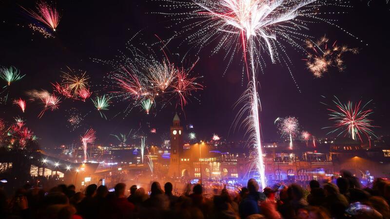 Ausgelassene Silvesterfeiern - teils schwere Zwischenfälle Zahlreiche Menschen feiern den Jahreswechsel auf Sankt Pauli über den Landungsbrücken am Hamburger Hafen.