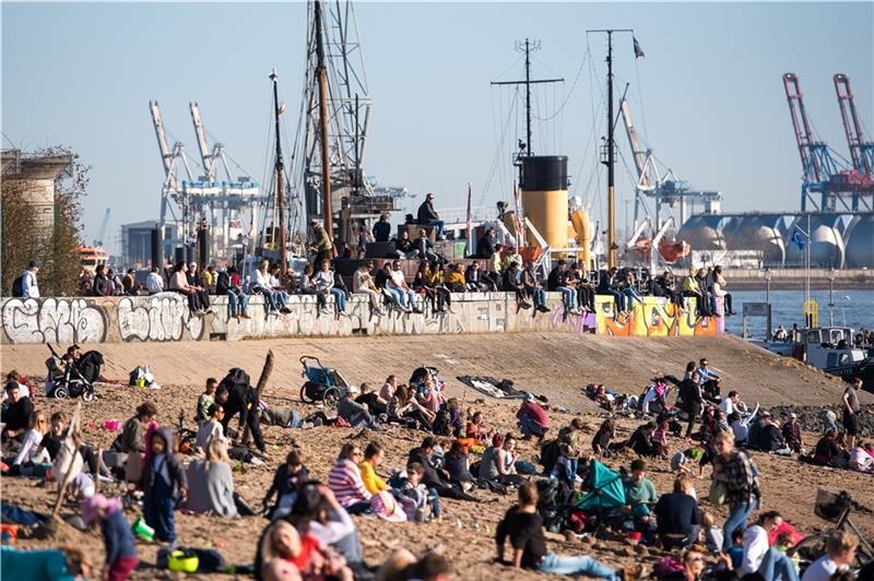 Zahlreiche Menschen genießen am Strand an der Elbe in Övelgönne die Sonne. Foto: Bockwoldt/dpa