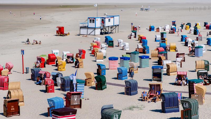 Zahlreiche Strandkörbe und Strandzelte stehen bei sonnigem Wetter am Strand der Insel Borkum.
