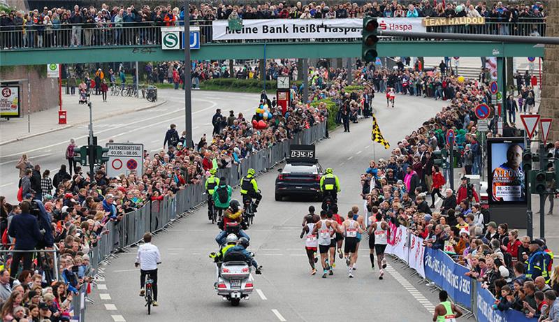 Kuriose Zieleinläufe beim Hamburg-Marathon – Verkehrschaos bleibt aus Zahlreiche Zuschauer verfolgen die Spitzengruppe an den Landungsbrücken. Rund 11.800 Teilnehmer nahmen an der 37. Auflage des Hamburg-Marathons teil. Foto: Christian Charisius/dpa