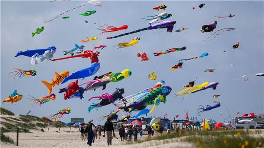 Zahlreiche bunte Drachen sind beim Drachenfest über dem Strand von St. Peter-Ording in der Luft. Zu sehen sind überdimensionale Kreationen, Lenkdrachen, Unikate und beliebte Comicfiguren.