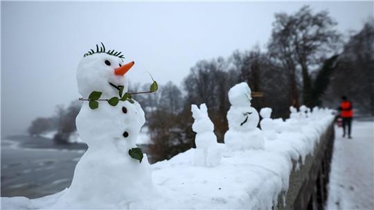Zahlreiche kleine und winzige Schneefiguren stehen auf einer Mauer der Krugkoppelbrücke an der Alster.