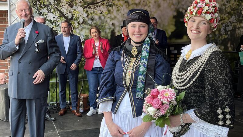 Zeremonienmeister Michel Rausch blickt auf die neue Altländer Blütenkönigin Linn Schuback (rechts) aus Mittelnkirchen und ihre Vorgängerin Anna-Sophie Sietas.