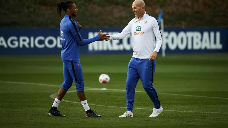 Zinedine Zidane (r) und Michael Olise klatschen sich ab.