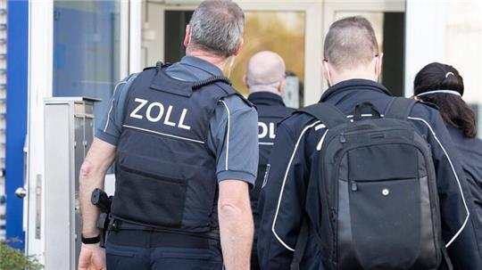 Zollbeamte betreten bei einer Razzia ein Gebäude.