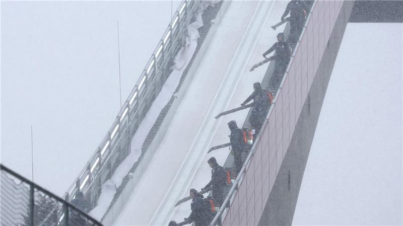 Zu viel des Guten: Mitarbeiter blasen beim Probedurchgang zur WM im Teamfliegen in Oberstdorf Schnee von der Flugschanze.