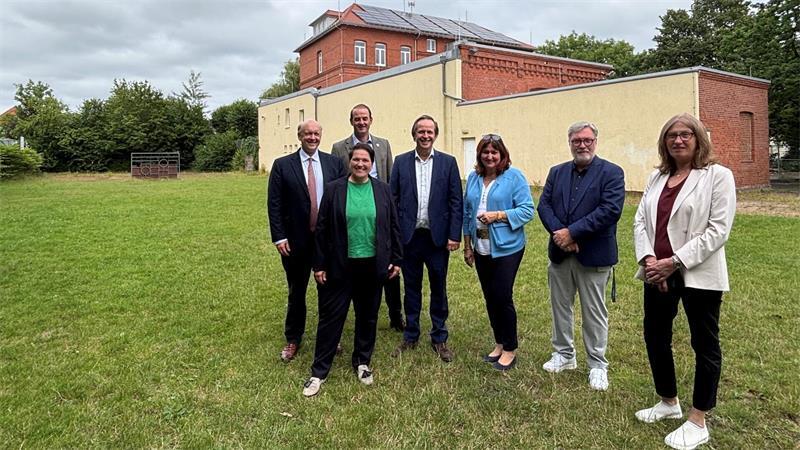 Neubau der Hochschule 21: So steht es um das Millionenprojekt Zum Gruppenbild mit ihren Gastgebern steht Niedersachsens Europaministerin Melanie Walter (2. von links) auf dem späteren Baufeld des geplanten Erweiterungsbaus der Hochschule 21. Der Neubau soll auf dem von der ehemaligen Albert-Schweitzer-Schule als Sportplatz genutzten Gelände entstehen.