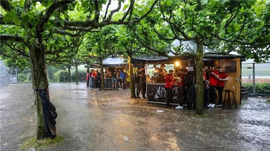 Zumindest ein bisschen Schutz: Fussballfans in Dortmund haben sich beim strömenden Regen an Imbissbuden untergestellt.