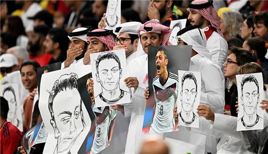 Zuschauer halten Bilder von Deutschlands ehemaligem Nationalspieler Mesut Özil in die Höhe. Foto: Federico Gambarini/dpa