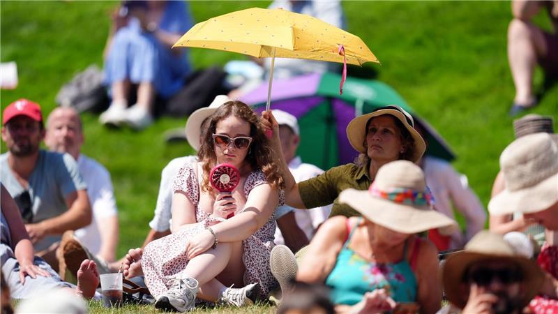 Zuschauer schützen sich gegen die Sonne und Hitze in Wimbledon.