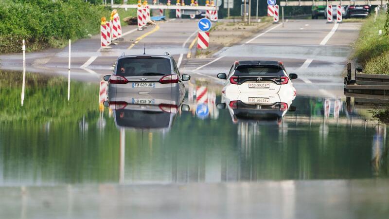 Zwei Autos stehen unter einer Saarbrücke in Saarbrücken im Hochwasser.