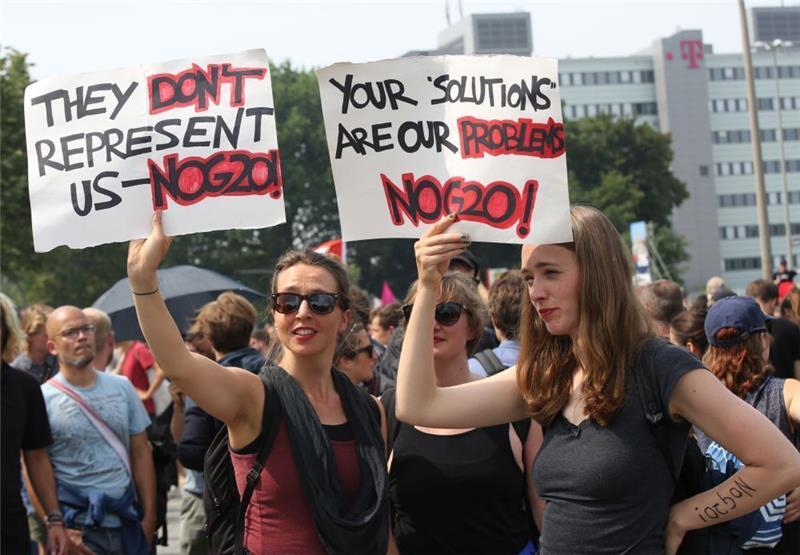 Liveticker zum Nachlesen: Der Gipfel ist beendet Zwei Demonstrantinnen halten bei einer Demo am Millerntorplatz in Hamburg Plakate mit der Aufschrift "They don't represent US-NOG20" und "Your Solutiona are our problems - NOG20". Foto: Bodo Marks/dpa