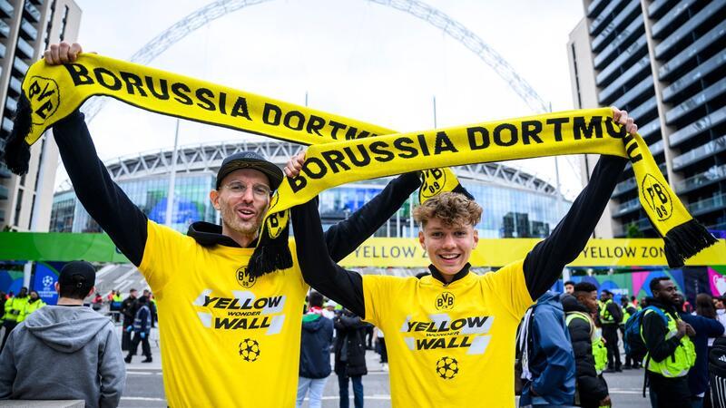 Zwei Fans von Borussia Dortmund stehen mit einem BVB-Fan-Schal vor dem Wembley-Stadion.