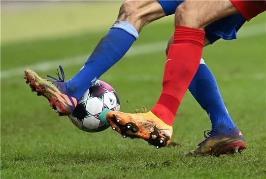 Zwei Fußballspieler kämpfen um den Ball.