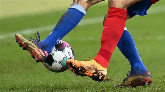 Zwei Fußballspieler kämpfen um den Ball.