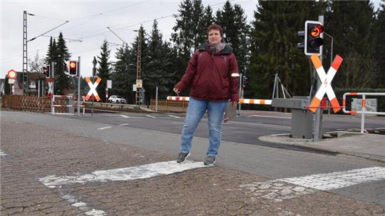 Zwei Haltelinien und Fahrbahnbegrenzungen auf einer Fahrspur: Anja Heckert (SPD), Ortsbürgermeisterin von Neukloster, steht an der umstrittenen Fahrbahnmarkierung am Bahnübergang Grüner Wald.