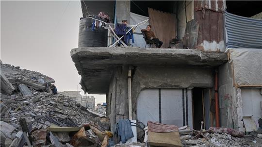 Zwei Mädchen sitzen neben einem Wäscheständer in einem ausgebrannten Wohnhaus.