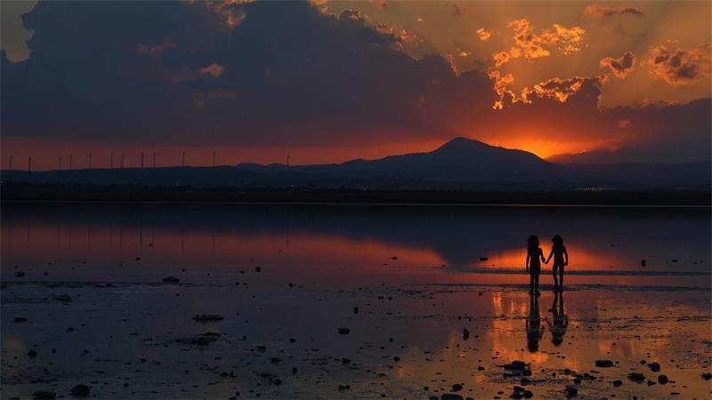 Zwei Mädchen spielen bei Sonnenuntergang am Salzsee in der südlichen Küstenstadt Larnaca auf Zypern.