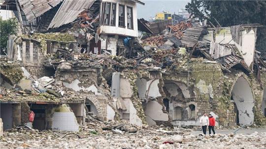 Zwei Männer gehen an einer völlig zerstörten Häuserzeile in Antakya vorbei. Im Zentrum der Stadt waren bei dem Beben vor einem Jahr unzählige Häuser zerstört oder beschädigt worden.
