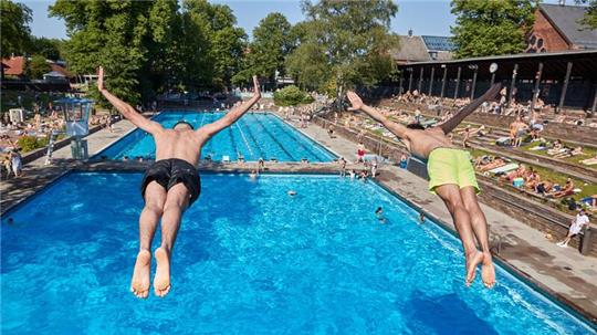 Zwei Männer springen vom Fünfmeter Turm in das Becken im Sommerfreibad Kaifu-Bad.