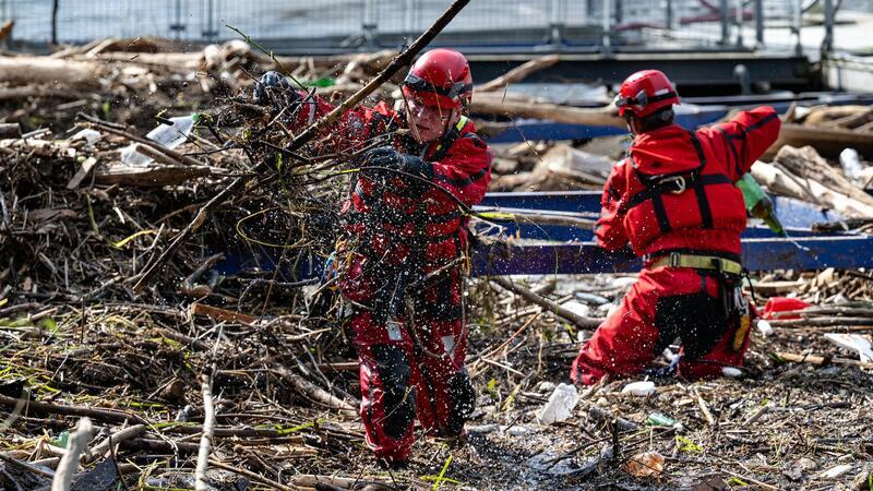 Zahl der Toten bei Hochwasser steigt auf mindestens 23 Zwei Personen entfernen nach dem Hochwasser Müll und Äste von einer Anlegestelle. (Archivbild)
