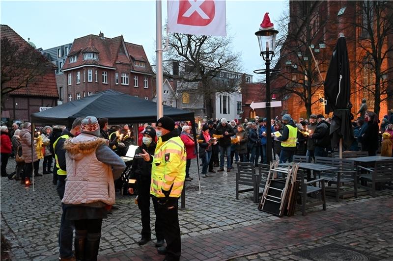Zwei Polizisten fordern die „buxaktiv“-Gruppe am Sonnabend bei ihrer Veranstaltung auf dem Buxtehuder St.-Petri-Platz auf, die städtischen Versammlungsauflagen einzuhalten. Foto: Vasel