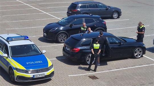 Zwei Polizistinnen und ein Polizist überprüfen auf einem Parkplatz die beiden Spendensammler. Foto: