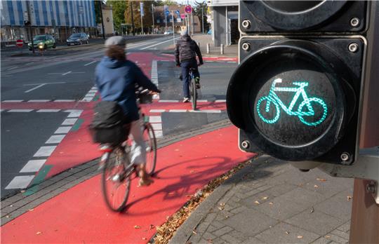 Zwei Radfahrer fahren auf dem Radweg an einer grünen Ampel vorbei. Fachleute haben eine stärkere Umwidmung von Verkehrsflächen zu Gunsten des Radverkehrs gefordert. Foto: Demy Becker/dpa