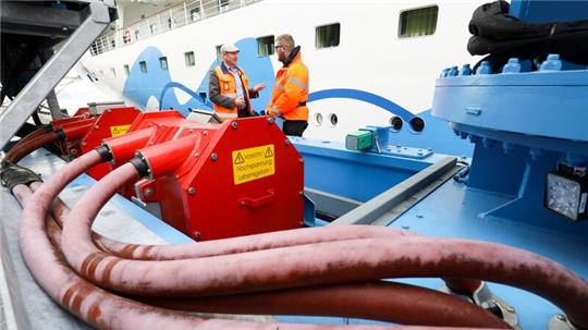 Zwei Servicetechniker stehen neben einem mobilen Kran der Landstromanlage am Cruise Center Altona die eine Stromverbindung zu dem Kreuzfahrtschiff „Aidasol“ gelegt hat.