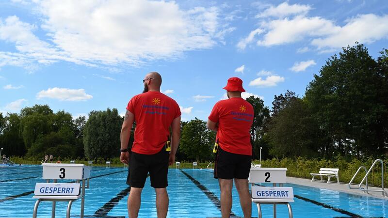 Zwei Sicherheitsmitarbeiter überblicken das Schwimmbecken.