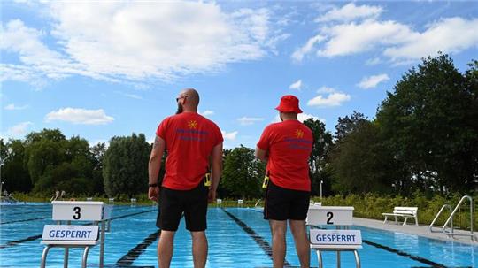 Zwei Sicherheitsmitarbeiter überblicken das Schwimmbecken.